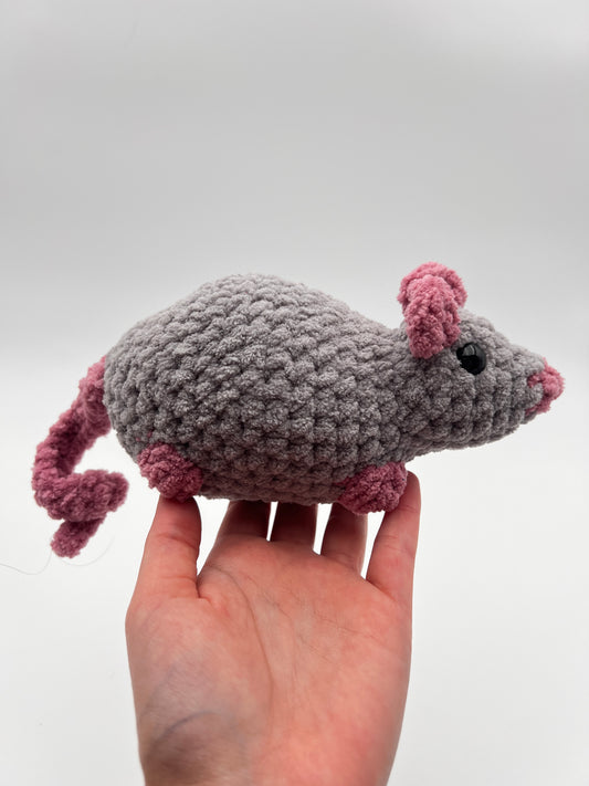 Hand holding a small crocheted mouse toy against a white background