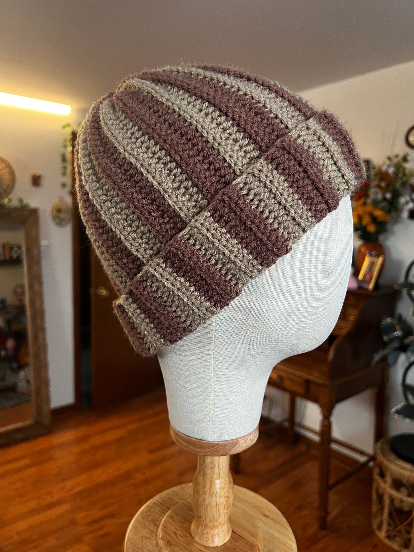 Crochet neutral beanie on a mannequin head with a blurred indoor background