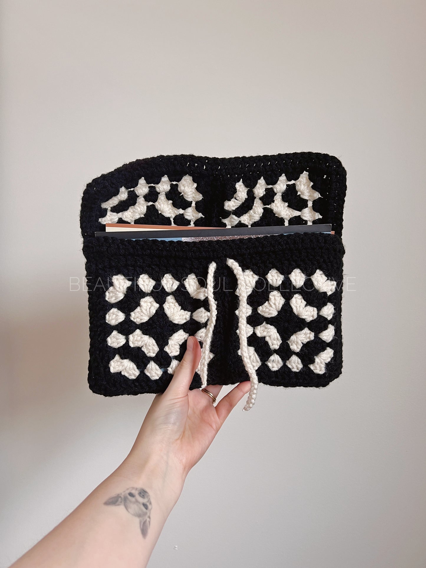 Black and white book sleeve held by a hand against a plain background