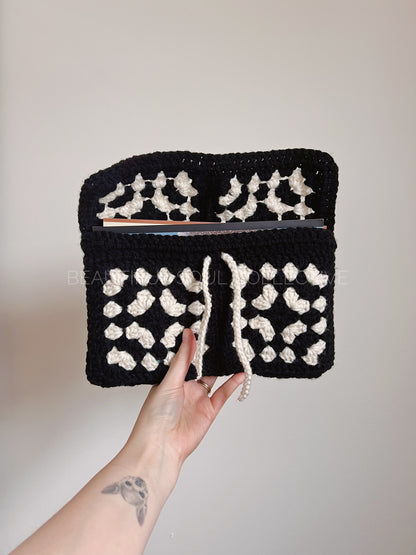 Black and white book sleeve held by a hand against a plain background