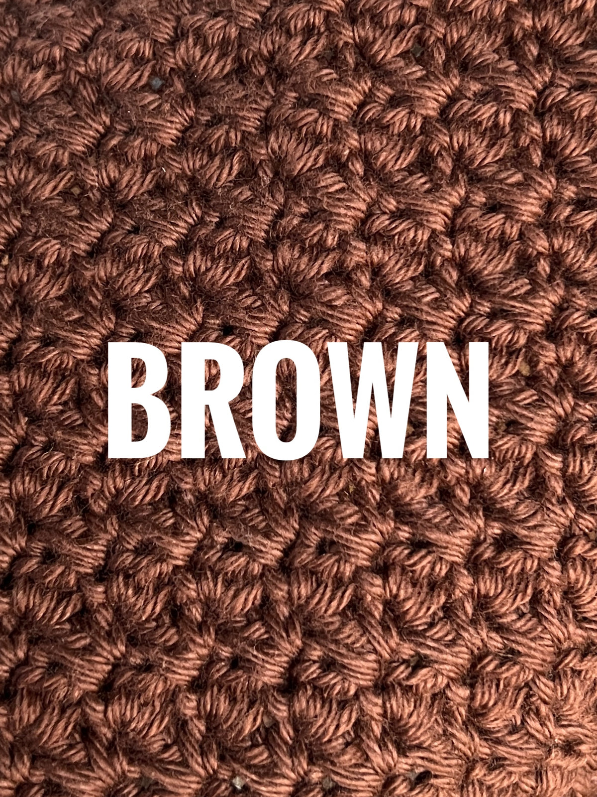 A close-up of a textured crochet washcloth swatch in a brown color, with the words 'BROWN' overlaid in large white text across the center.