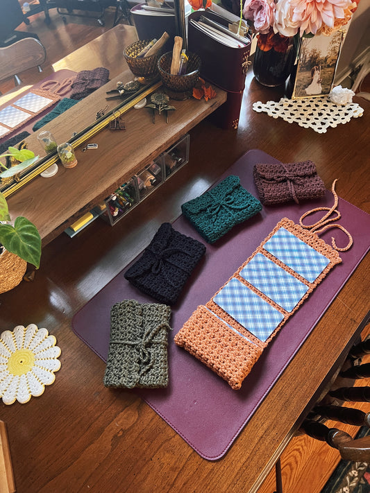 Tarot Card Roll-up pouches in orange, olive, black, teal and brown on a desk with various decor