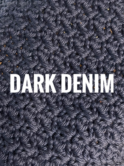 A close-up of a textured crochet washcloth swatch in a denim blue color, with the words 'DARK DENIM' overlaid in large white text across the center.