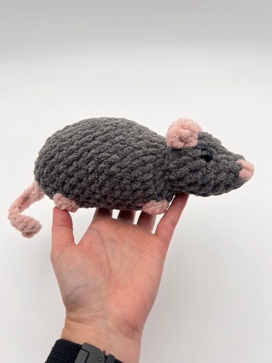 Hand holding a rat stuffed animal against a white background