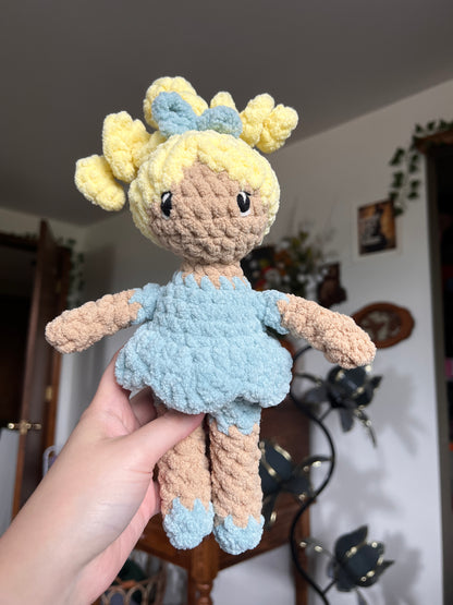 Crochet doll with beige skin and blonde hair. Blue bow, dress and shoes. The eyes are embroidered.