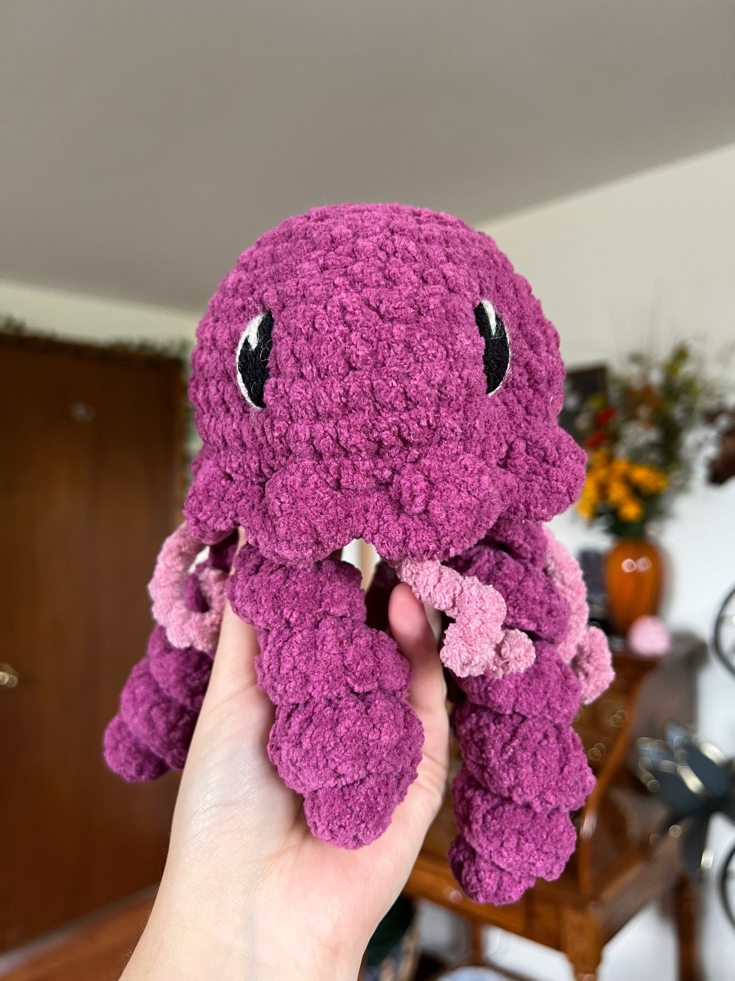 Crochet jellyfish in a magenta and pink yarn with embroidered eyes