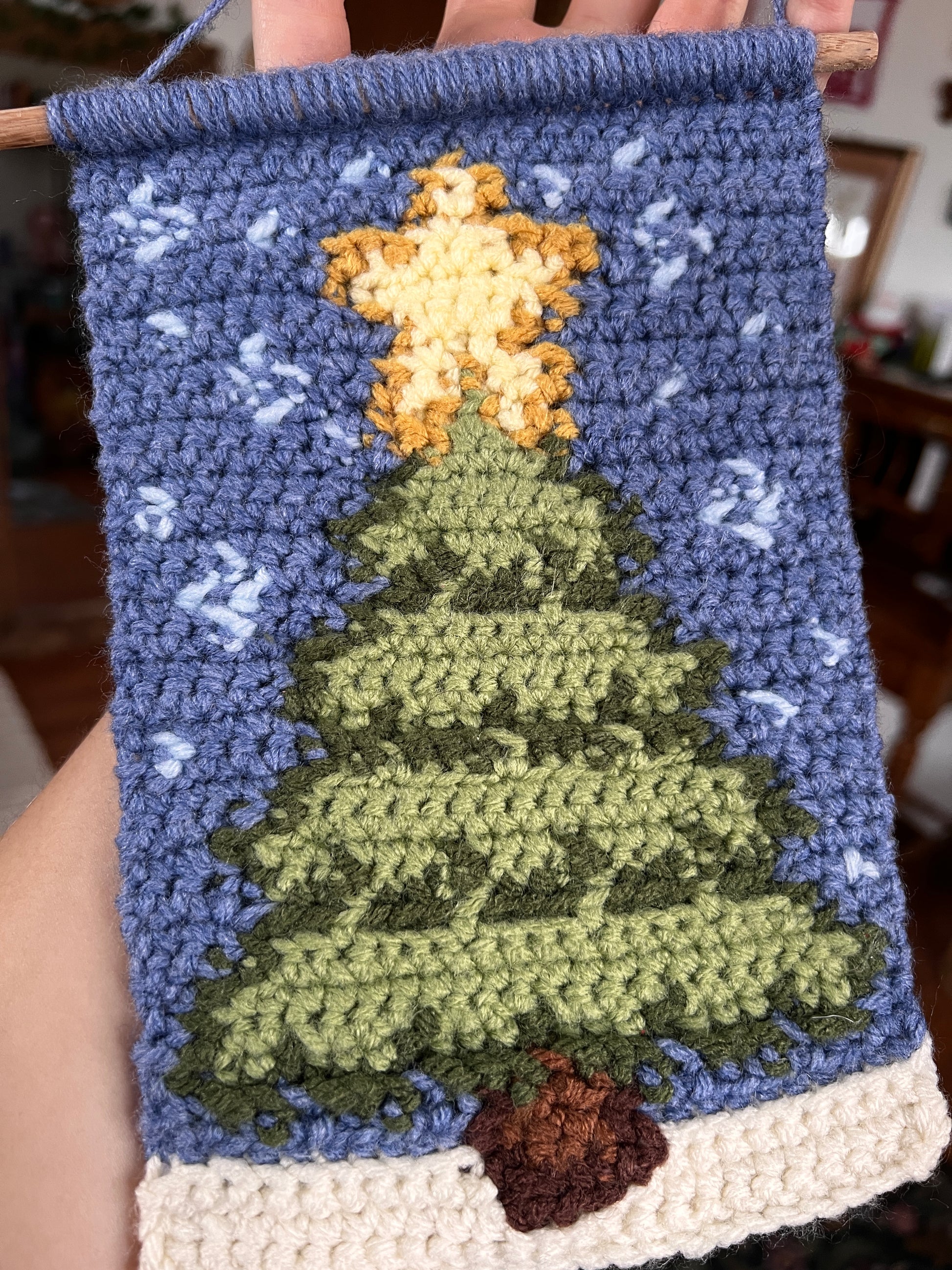 Handmade woven textile with Christmas tree and snow on a blue background.