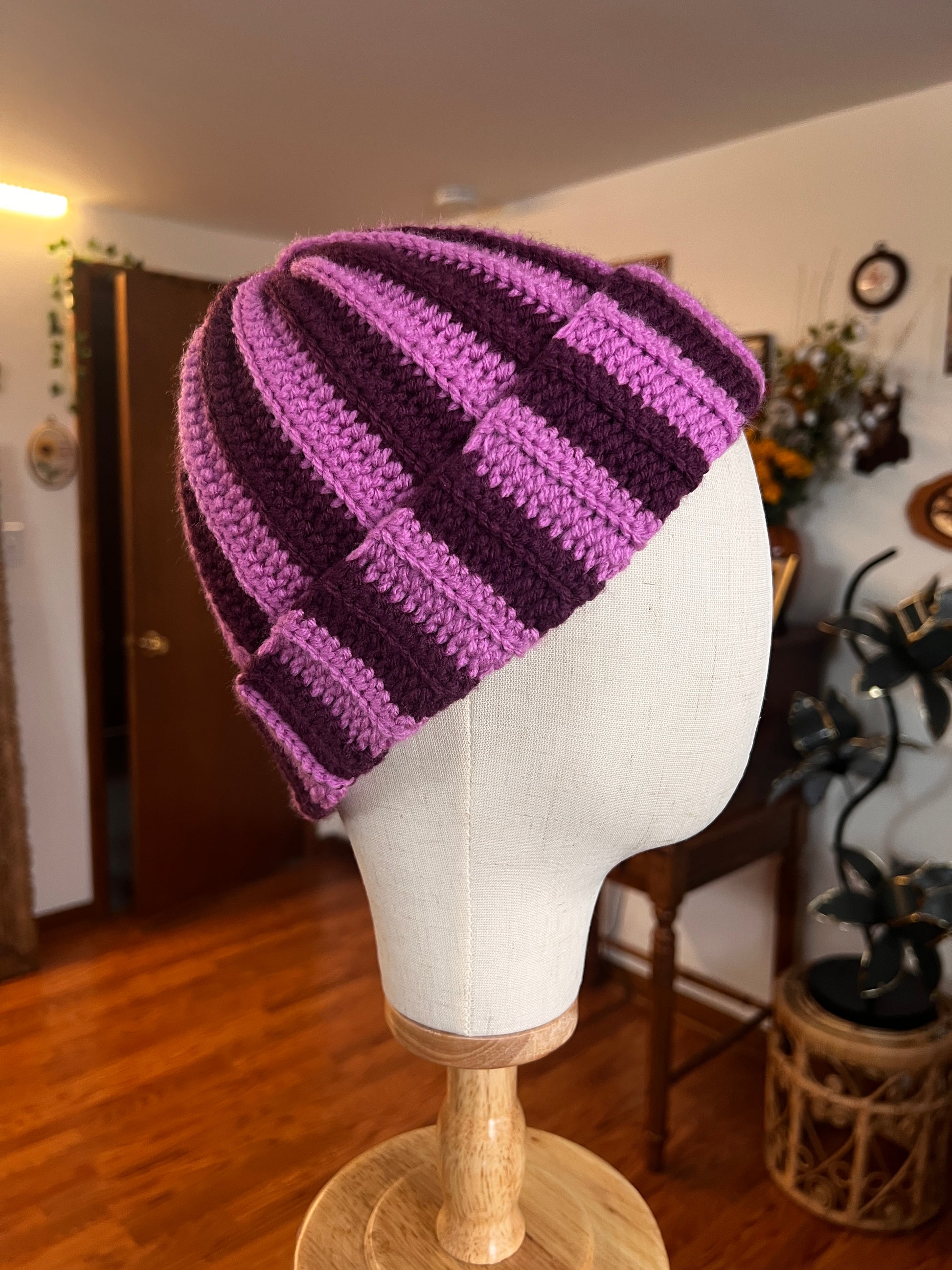 Purple striped beanie on a mannequin head with a blurred indoor background