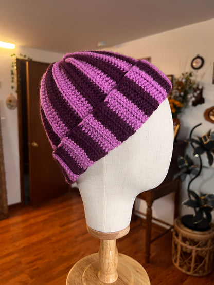 Purple striped beanie on a mannequin head with a blurred indoor background