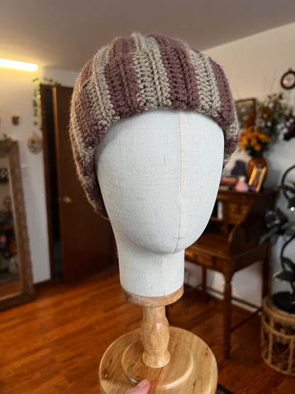 Mannequin head with brown striped beanie and wooden stand in a room setting
