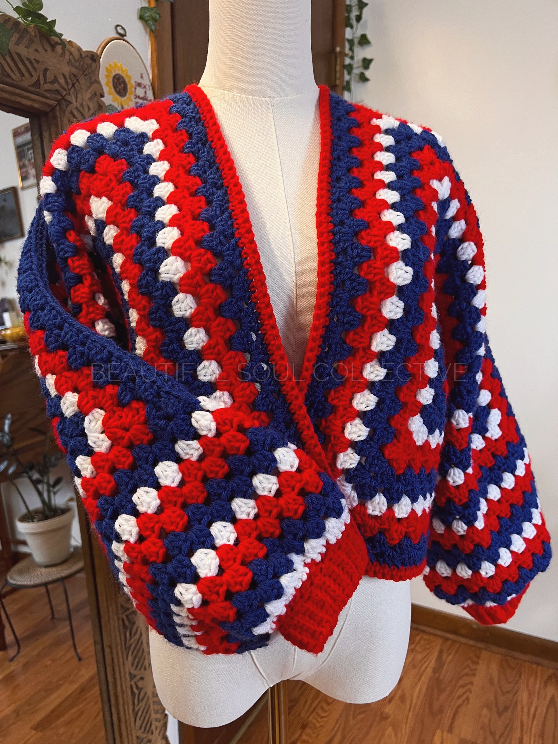 Crochet cardigan in red, white and blue yarn on a mannequin