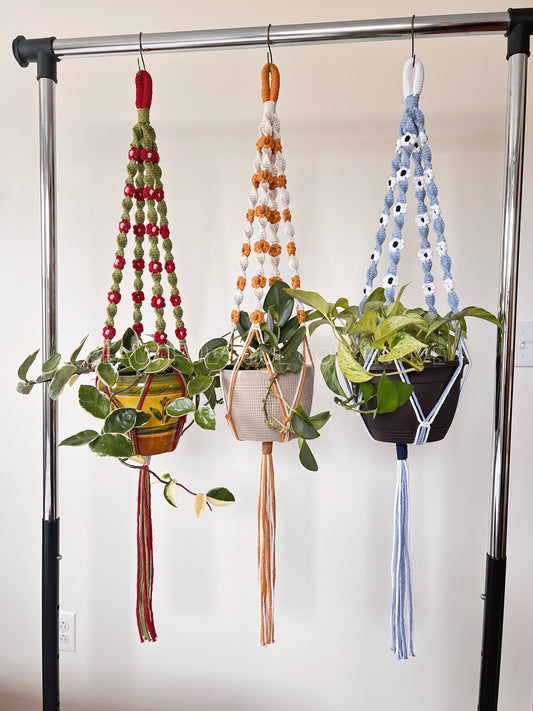 Three hanging planters with colorful flowers and spiral design on a stand.