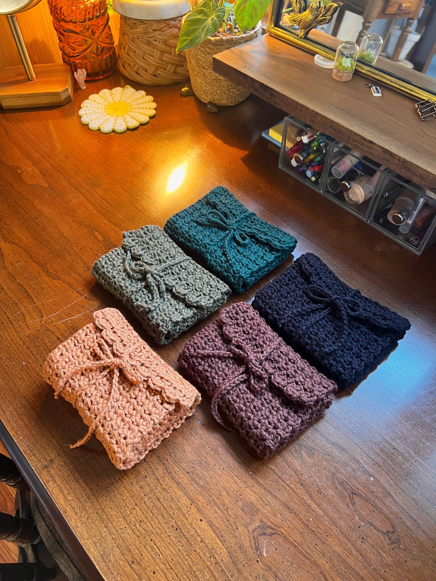 Set of crocheted pouches in various colors on a wooden surface.