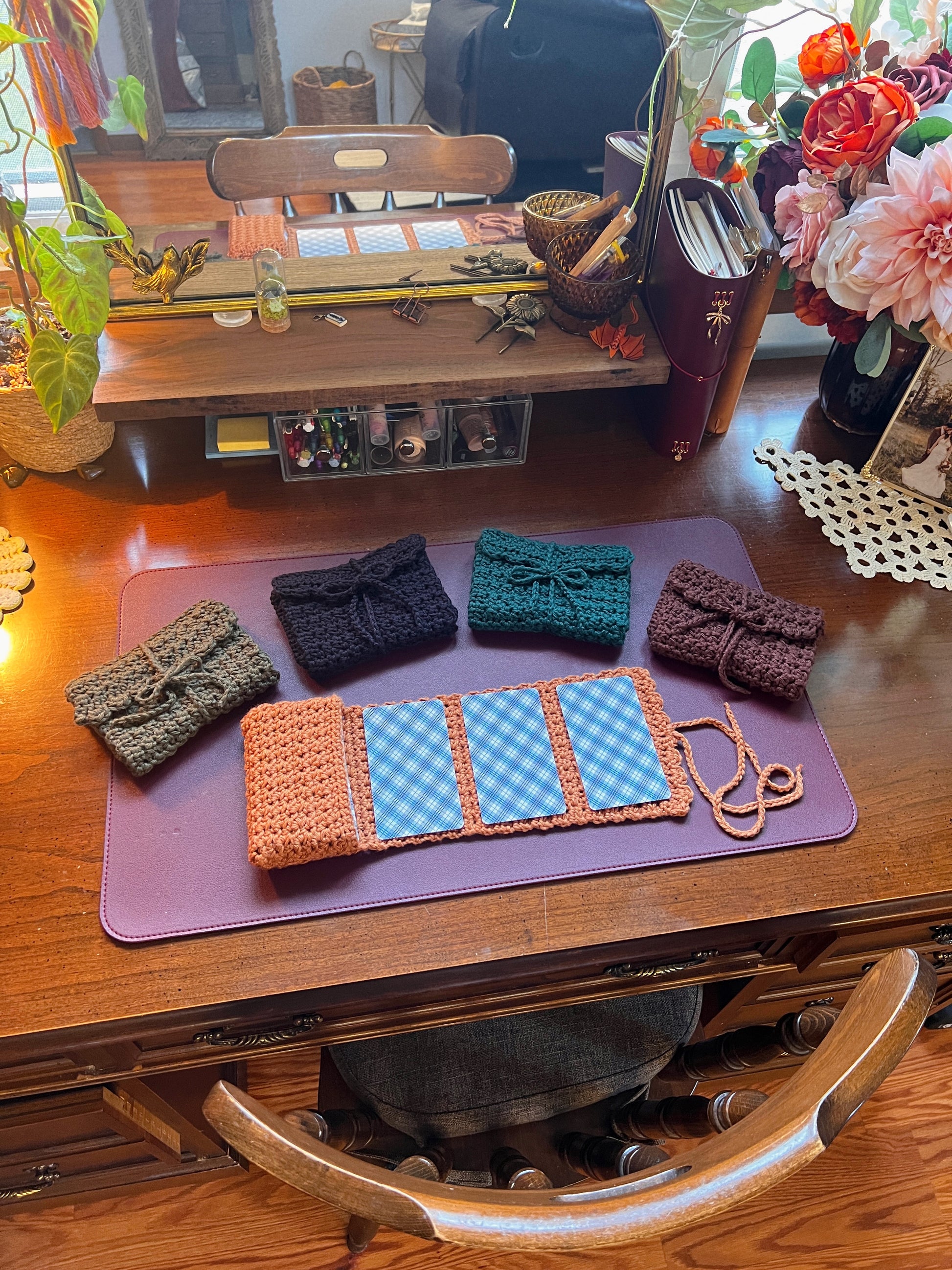 Collection of crocheted tarot card pouches on a purple mat with decor on a desk