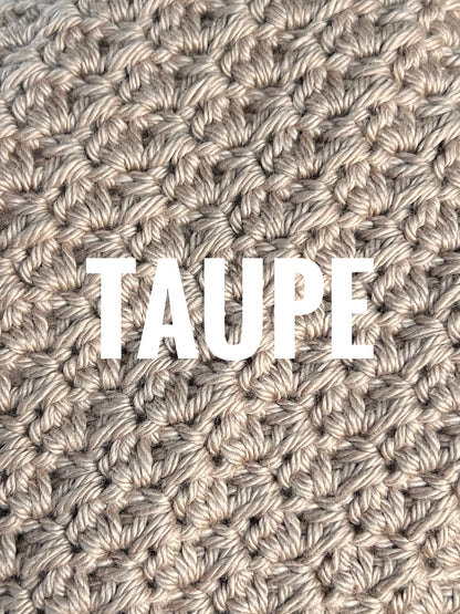 A close-up of a textured crochet washcloth swatch in a taupe color, with the words 'TAUPE' overlaid in large white text across the center.