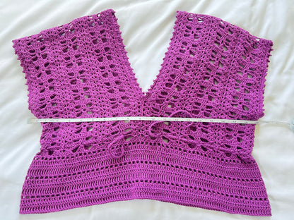 A purple crochet short sleeve top with measuring tape showing the width
